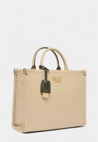 Borsa a mano in pelle beige con due manici superiori, dettagli in oro e una targhetta marrone con un logo. Forma quadrata e tessuto liscio.