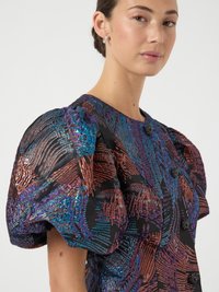 Top con maniche a sbuffo caratterizzato da una base in tessuto nero con motivi multicolori e texture in blu, bronzo e viola. Bottoni neri inclusi.