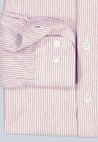 Weißes Hemd mit feinen roten und blauen Streifen, mit Knopfmanschetten und weißen Knöpfen. Der Stoff erscheint glatt mit einem klassischen Kragen und ordentlich gefalteten Ärmeln.