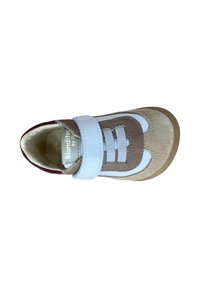 Zapatilla para niño pequeño en ante y cuero beige y blanco, con cinta de velcro y cordones elásticos, vista desde arriba sobre un fondo blanco.