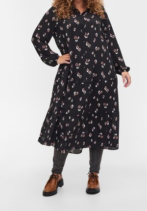 Une robe noire avec un col et des manches longues, ornée d'un motif floral en blanc et rose. Le design comprend des couches superposées au niveau de l'ourlet.