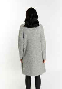 Lungo cardigan grigio lavorato a maglia con accenti di perle sulle spalle; presenta polsini e orlo a coste, texture morbida e vestibilità rilassata.