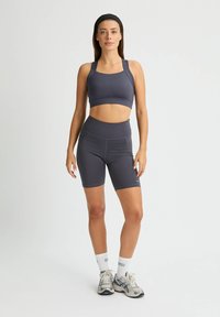Mörkgrå atletisk tvådelad set med en kort topp med breda band och högmidjade cykelbyxor. Mjuk, elastisk tyg.