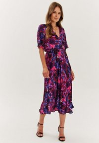 Kwiatowa sukienka midi z głębokim dekoltem w kształcie litery V, krótkimi rękawami i zwiewną sylwetką. Kolory obejmują purpurę, róż i czerń. Satynowa faktura.