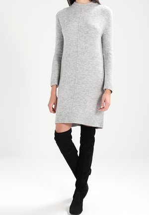 Abito grigio lavorato a maglia con maniche lunghe, orlo a coste e silhouette dritta. Abbinato a stivali in suede neri sopra il ginocchio.