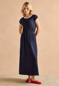 Námornícky maxi šaty s krátkymi Rolovanými rukávmi a elastickým pásom. Hladká tkanina, ľahká. V kombinácii s červenými plochými topánkami. Jednoduchý dizajn.