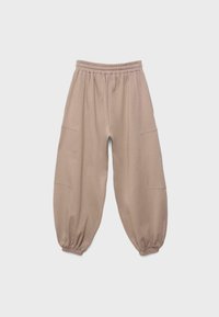 Beige Sweatpants mit lockerer Passform, elastischem Bund, Seitentaschen und elastischen Bündchen, vor einem schlichten hellen Hintergrund dargestellt.