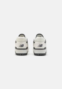 Hvide og grå atletik-sko har en tekstureret sål, logo-detaljer og en polstret krave for komfort og støtte.