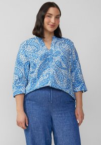 Blouse met een blauw patroon, V-hals, 3/4 mouwen en een ontspannen fit. De stof heeft een mix van lichte en donkere blauwe ontwerpen.