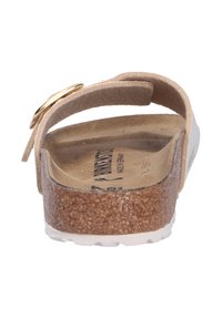 Sandal en suédine beige avec une semelle en liège et une semelle en caoutchouc blanche. Dispose d'une seule sangle avec un accent en boucle dorée. Design plat, dos ouvert.