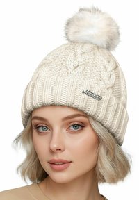 Cream cable-knit beanie with a fold-over brim and a fluffy pom-pom on top. Features a small silver logo accent on the front.
