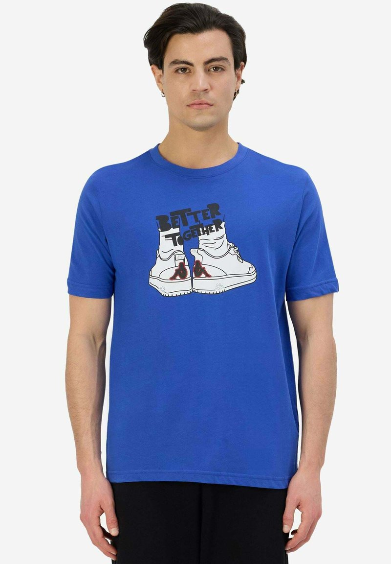 T-shirt in cotone blu con una stampa grafica di sneakers e la scritta "UNITE È MEGLIO" in nero, con maniche corte e scollo rotondo.