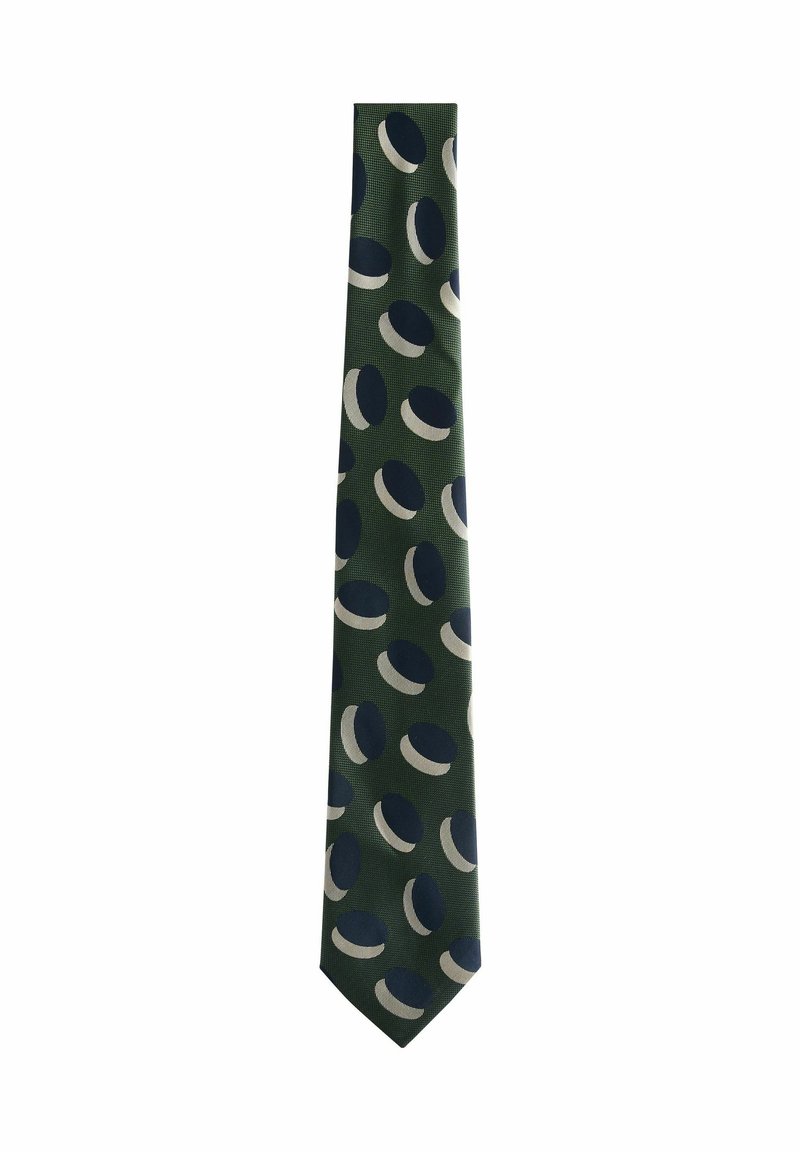 Groene stropdas met een patroon van afwisselende marineblauwe en witte cirkels. Gemaakt van soepel stof met een smal, puntig uiteinde.