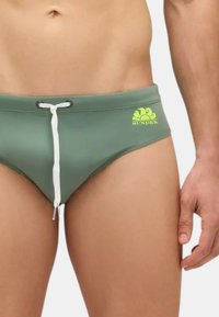 Slip da bagno verde realizzato in materiale elasticizzato, con coulisse bianca e logo "Sundek" giallo neon sul lato.