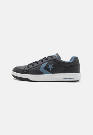 Baskets basses noires Converse avec logo étoile et chevron bleu, semelle blanche, lacets noirs et doublure intérieure bleue, vues de côté.
