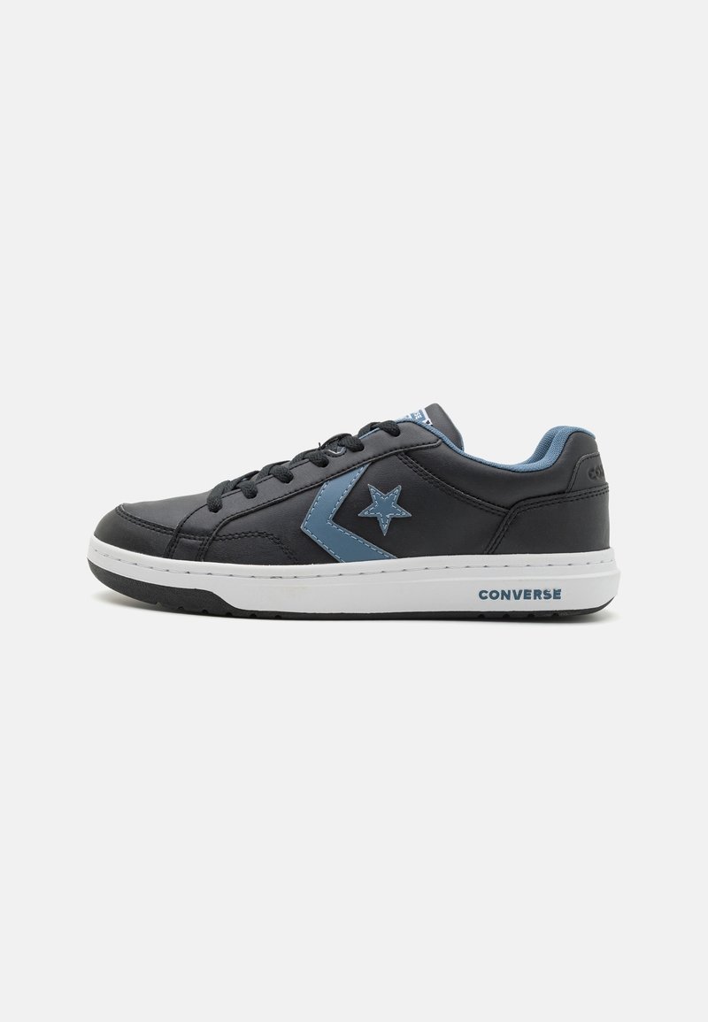 Baskets basses noires Converse avec logo étoile et chevron bleu, semelle blanche, lacets noirs et doublure intérieure bleue, vues de côté.
