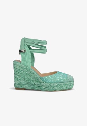 Mintgroene espadrille sleehak met gevlochten jute zool, bovenwerk van gestructureerde stof en enkelbandjes. Voorzien van decoratieve studs op de neus.