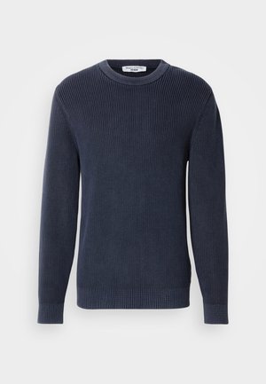 Mornarsko plavi rebrasti džemper s dugim rukavima i okruglim izrezom. Karakterizira ga teksturirani materijal i priliježući kroj. Etiketa je vidljiva na izrezu oko vrata.