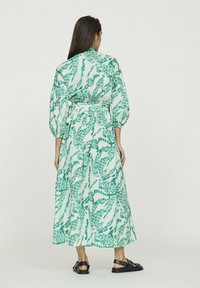 Robe longue verte et blanche avec un motif botanique, dotée de manches bouffantes et d'une taille ceinturée. Fabriquée dans un tissu léger.