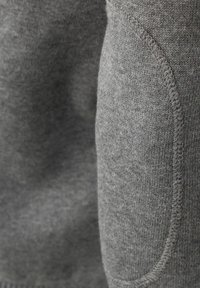 Grauer Pullover, gestrickte Textur, abgerundete aufgesetzte Tasche, sichtbare Nähte, weicher Stoff. Keine auffälligen Muster oder Akzente.