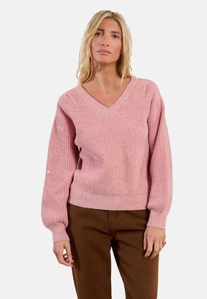 Maglione a coste rosa chiaro con scollo a V, maniche lunghe e una trama sottile. Indossato sopra pantaloni marroni, presenta una vestibilità morbida e un tessuto delicato.