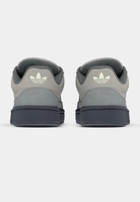 Γκρι σουέντ αθλητικά παπούτσια με σκούρα λαστιχένια σόλα, με αχνό λογότυπο στη φτέρνα και επενδεδυμένο γιακά για άνεση.