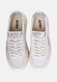 Witte leren sneakers met geperforeerd ontwerp, platte katoenen veters, lichtgrijze accenten en een beige rubberen zool. Merknaam "AUTRY" op de tong.