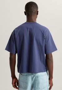Navyblaue Kurzarm-T-Shirt aus Baumwolle mit lässiger Passform, geradem Saum und minimalen Nähten auf der Rückseite.