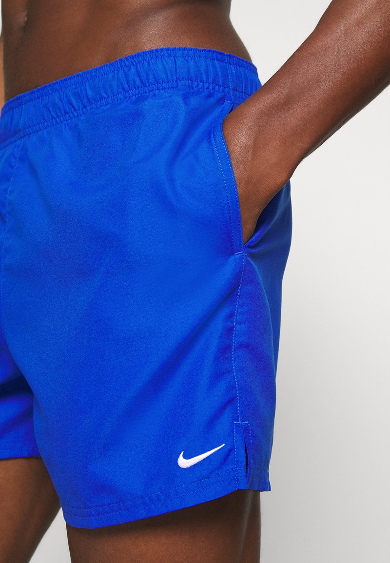 Shorts de sport bleus en tissu léger, avec une taille élastique, une poche latérale et un logo Nike blanc sur l'ourlet.