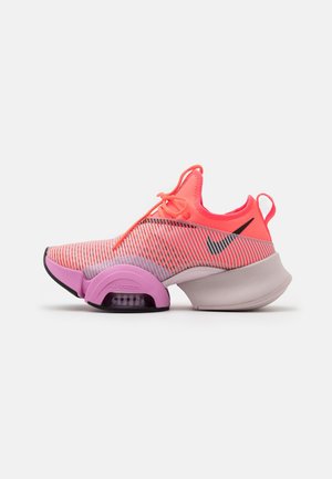 Chaussure de sport rose vif et violette avec tige rayée, semelle épaisse avec amorti à air visible, et logo Nike noir sur le côté.