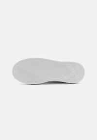 White sneaker sole with textured rubber surface, featuring ridged patterns and logo detail, rounded front edge, and flat back for stability.