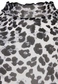 Tissu imprimé léopard noir et blanc avec une texture transparente et un bord froncé en haut.