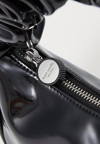 Mustmustest musta nahast saapad läikiva viimistlusega, hõbedase tõmbluku ja logo detailiga. Tekstuuritud kangas ja tõmblukukujundused rõhutavad disaini.