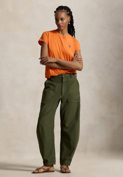 Κοντομάνικο, φωτεινό πορτοκαλί βαμβακερό μπλουζάκι συνδυασμένο με χαλαρό, ελαιδί cargo παντελόνι με εμπρόσθιες τσέπες και άνετη εφαρμογή.