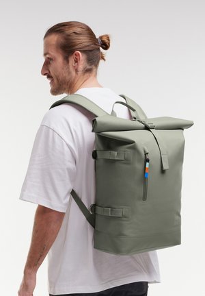 Zaino roll-top in verde tenue, realizzato in materiale resistente. Presenta spallacci regolabili, tasca laterale e una finitura testurizzata.