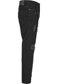 Mustat farkut, joissa on slim fit -leikkaus, etuosassa kuluneet repeämät ja klassinen viisi-taskuinen muotoilu. Nahkapatchi vyötäröllä.