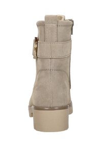 Beige suède enkellaars met blokhak, achterrits en decoratieve zijriem met een rechthoekige gesp.