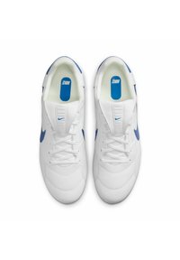 Zapatillas deportivas blancas con acentos azules, con una parte superior texturizada, cierre de cordones y lengüeta acolchada, mostrando el logotipo de Nike en la plantilla.