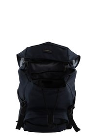 Navy fabric backpack with adjustable straps, drawstring closure, and a large opening. Features interior pockets and a smooth texture.