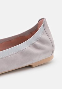 Ballerine en daim gris doux avec bord élastique et semelle plate beige clair, vue de côté et de dos sur fond blanc.