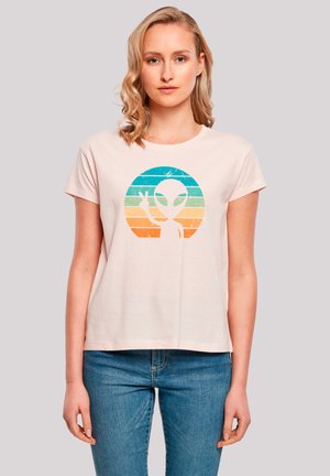 Helles rosa Baumwoll-T-Shirt mit kurzen Ärmeln, das ein Alien-Design in Blau, Grün, Orange und Weiß zeigt, eingerahmt in einem kreisförmigen Motiv.