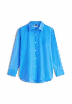 Hellblaues, langärmliges Hemd mit Knöpfen und Kragen, besticktem Logo auf der Brust und kleinem Logo an der linken Manschette, dargestellt auf weißem Hintergrund.