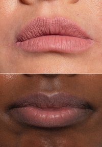Due set di labbra sono mostrati. La parte superiore ha un colore rosa opaco e morbido con una superficie texturizzata. La parte inferiore ha tonalità grigio-violetto attenuate con una finitura liscia.