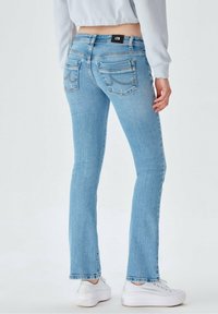 Světle modré džíny z denimu s úzkým střihem, pěti kapsami a jemnými šitími detaily. Má značkový pas a mírné rozšíření na nohavicích.