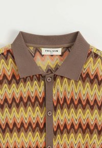 Polo en tricot à motif zigzag coloré, avec un col et des boutons marron, présentant une texture légère et à mailles ouvertes. Marque : FRILIVIN.