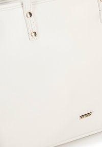Witte lederen tote bag met twee handvatten aan de bovenkant, gouden hardware accenten en een klein merkembleem. Gladde textuur met een minimalistisch ontwerp.