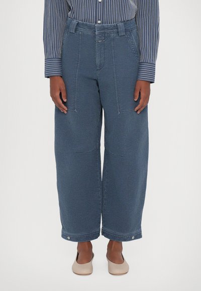 Pantaloni larghi blu realizzati in tessuto texturizzato, con ampie tasche frontali, vita cincturata e dettagli con bottoni a pressione all'orlo.
