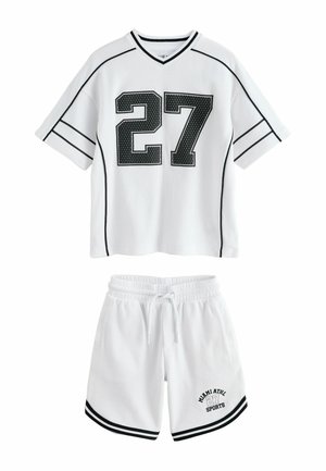 Biała sportowa siateczkowa koszulka z czarnym numerem 27, dopasowane białe spodenki z czarnym obszyciem i napisem "Miami ATHL 27 Sports" na nogawce.