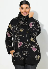 Sweat-shirt noir avec des motifs de visage abstrait et d'étoiles en or, rose et crème, avec un col montant et des poches latérales. Tissu doux.