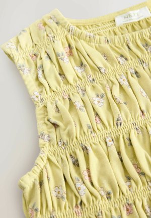 Gelbes Blumenshirt aus weichem Stoff, mit Rüschendetails und kurzen Ärmeln. Das Muster umfasst kleine rosa und grüne Blumen.